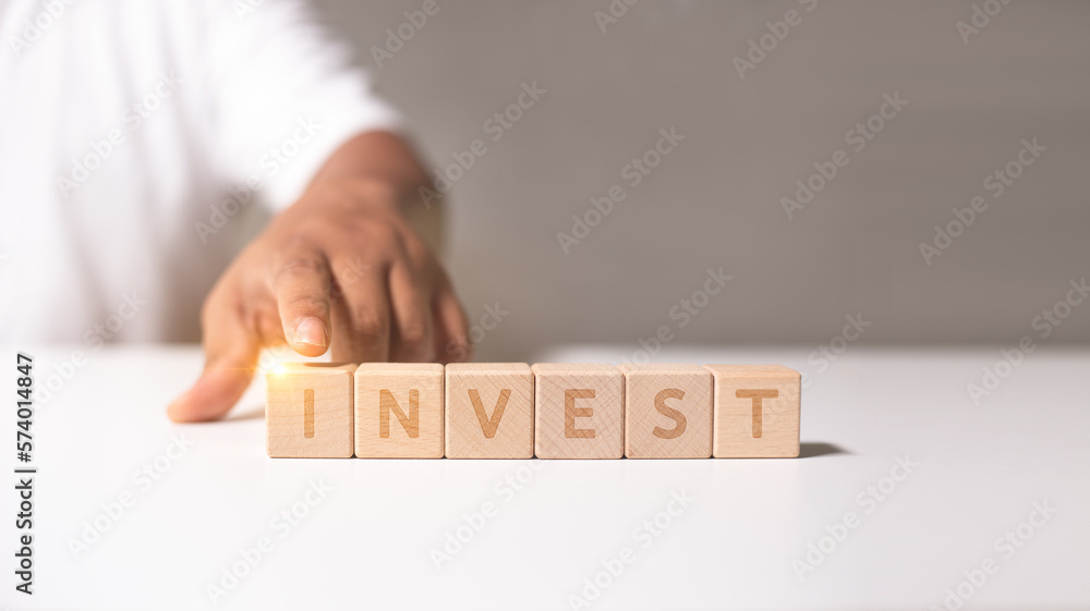 Invest text on wooden block, Hand holding wooden word for business success. Invest management or goal of business ideas. Invest text on wooden block, Hand holding wooden word for business success. Invest management or goal of business ideas.