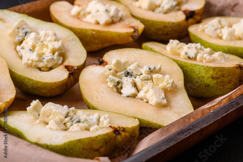 Delicious baked pear with dorblu cheese, walnut and honey on a textured concrete background