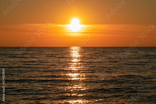 Panoramic sunset view from Sveti Stefan at Adriatic Mediterranean Sea, Budva Riviera, Montenegro, Europe. Reflection of sun beams on water surface during twilight. Summer vacation in seaside resort