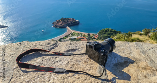 Canvastavla Tourist camera on viewing platform at chapel Saint Sava with aerial scenic view of idyllic island Sveti Stefan in Budva Bay, Adriatic Mediterranean Sea, Montenegro, Europe