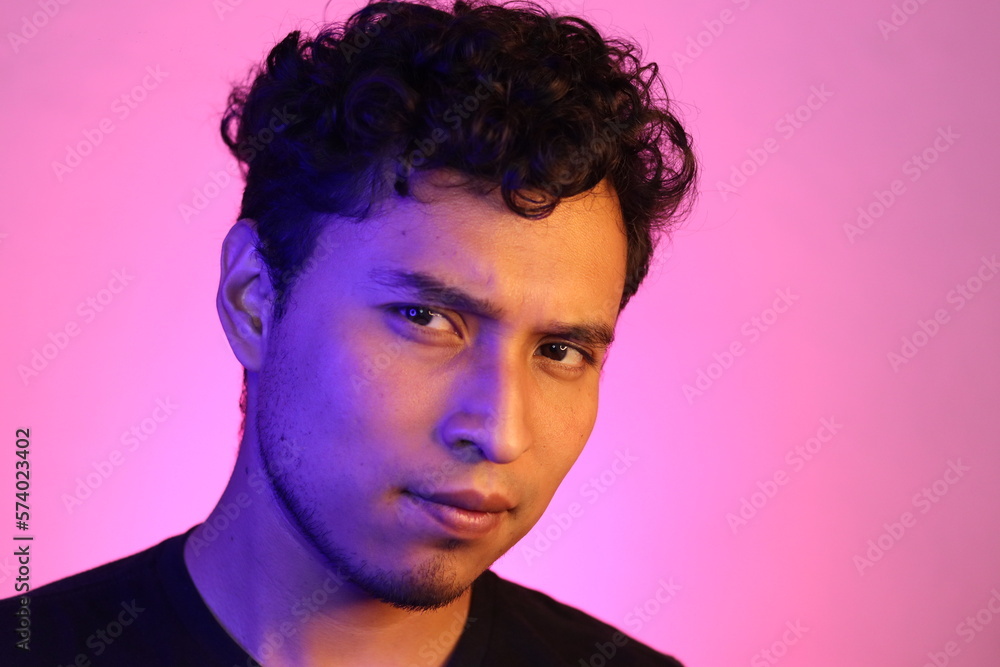 joven latino determinado posando en un fondo rosado