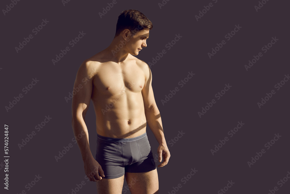Fototapeta premium Sporty sexy young man in underwear isolated on black studio background. Toned fit male model in underclothing wear advertise good quality clothing. Body shape and fitness concept.