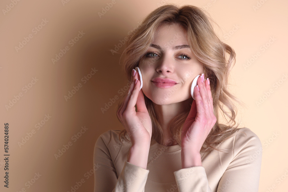 Removing makeup with cotton pads. Cleaning face with pad. Cosmetic cotton pad. Young woman caring for facial skin using cotton pad in studio. Beauty care and pampering. Daily skincare. Removing makeup with cotton pads. Cleaning face with pad. Cosmetic cotton pad. Young woman caring for facial skin using cotton pad in studio. Beauty care and pampering. Daily skincare.