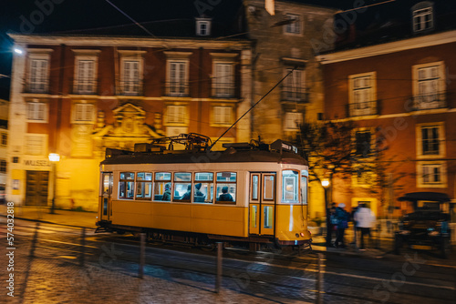 Lisbon tram in motion, panning, driving at night, blurry background