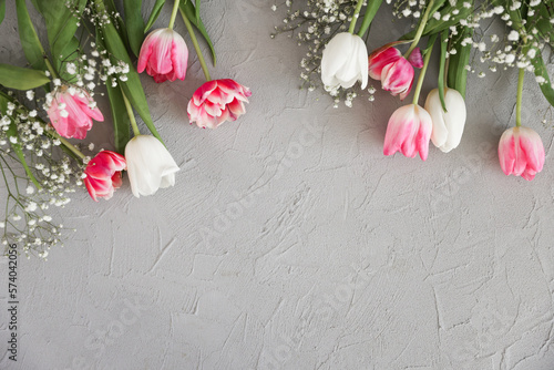Fototapeta Naklejka Na Ścianę i Meble -  Pink tulips and white gypsophila flowers bouquet on a stylish gray stone background. Mothers Day, birthday celebration concept. Copy space for text