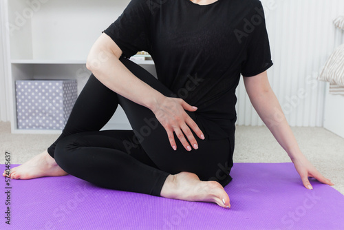 Young attractive woman practicing yoga, working out, wearing sportswear, black top and pants, indoor full length, studio background. Sport and healthy active lifestyle concept.