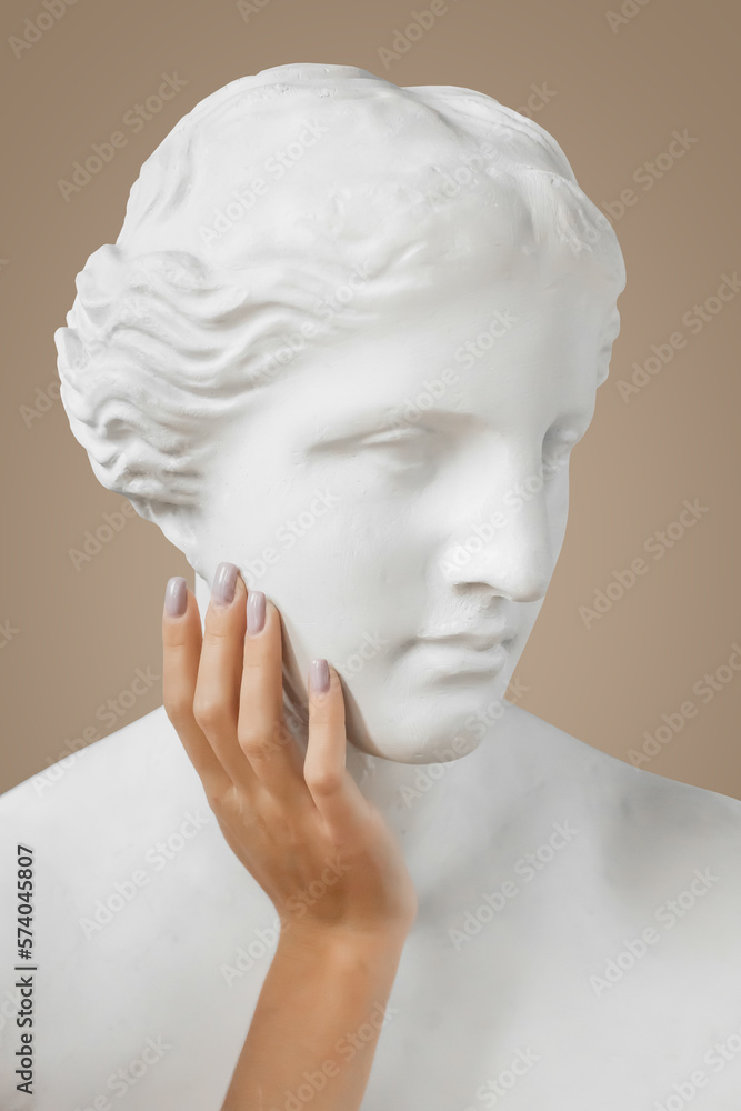 Venus sculpture with human woman's hand on beige background Venus sculpture with human woman's hand on beige background