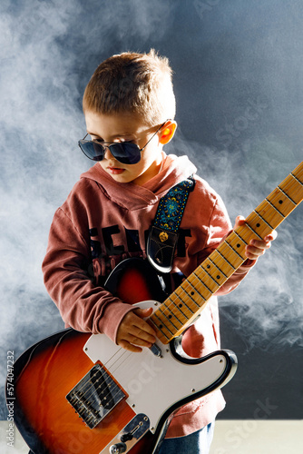 Dziecko gra na gitarze elektrycznej - rockowy chłopiec w studiu - zespół muzyczny - mały muzyk photo