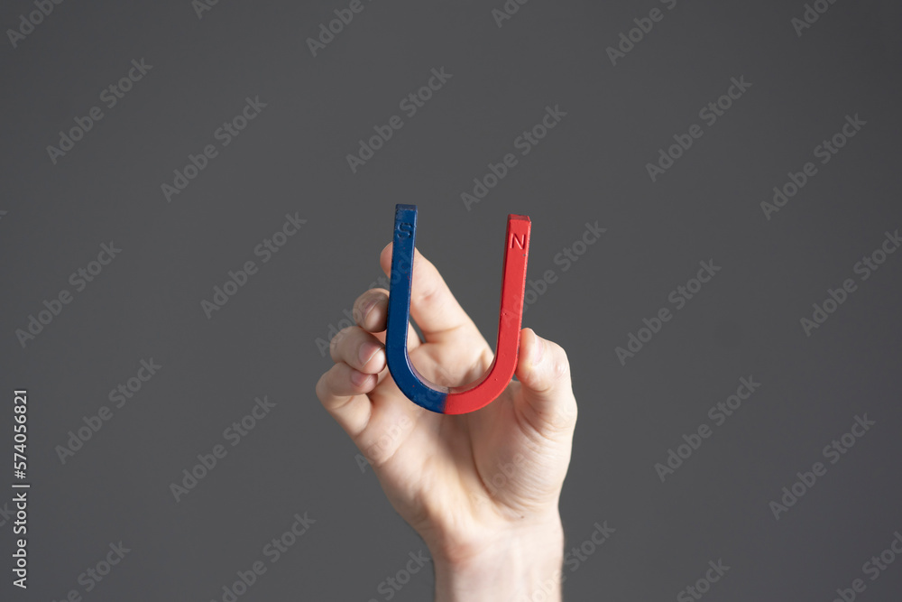 student holding a blue and red magnet in shape of horseshoe, making science tests student holding a blue and red magnet in shape of horseshoe, making science tests