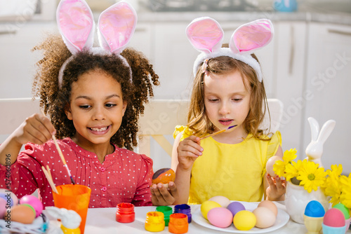 Two girls paint Easter eggs for holiday at home