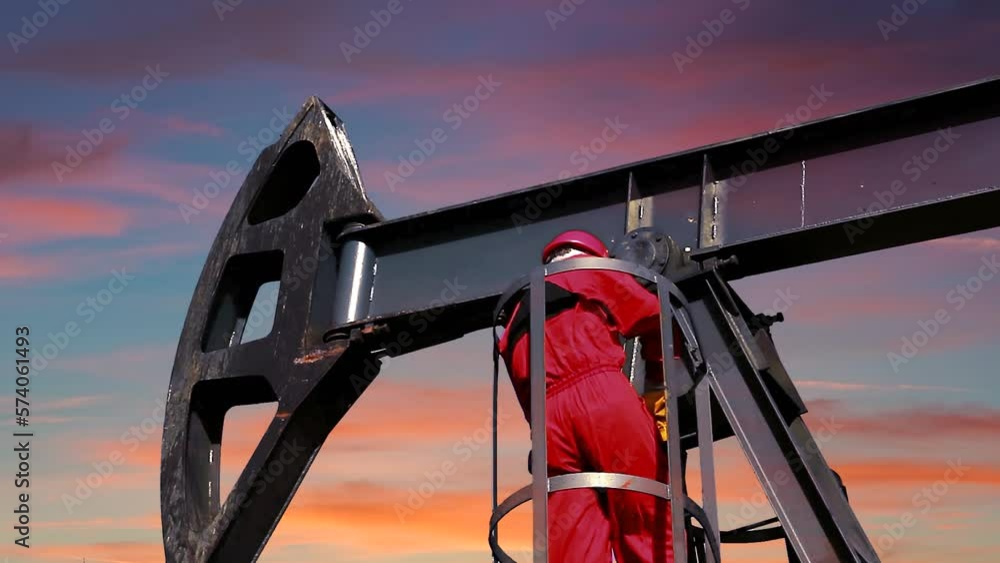 Oil Worker Climbing Down the Pump Jack at Sunset Oil Worker Climbing Down the Pump Jack at Sunset
