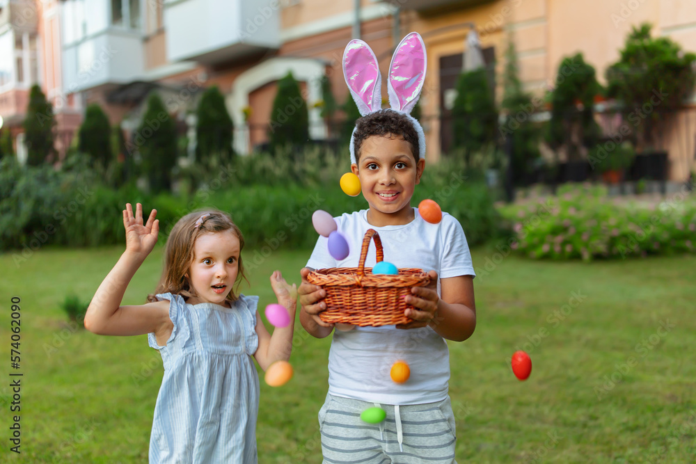 A two kids during Easter egg hunt and plaing Easter eggs and a baskets - obrazy, fototapety, plakaty 