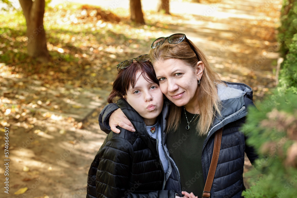 Mother and teenage daughter are happy in the park, taking pictures, hugging and talking. With the help of the mother, the daughter passes the teenage period easily
