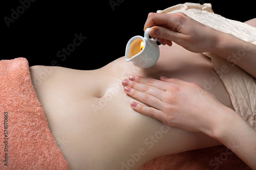 naked belly of a girl in a spa salon with a towel and candles. concept of body care, relaxation and stress relief
