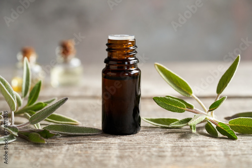 A bottle of sage essential oil with sage twigs