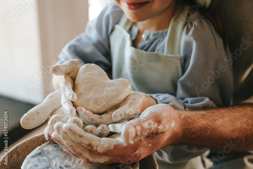 Foto Little girl working with clay on potter's wheel