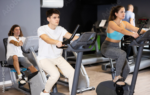 Mature man doing cardio workout out at gym, training on exercise bikes