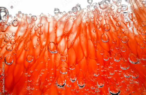 Grapefruit slice peeled pulpy capsules in water with air bubbles, in background light, close-up selective focus photo