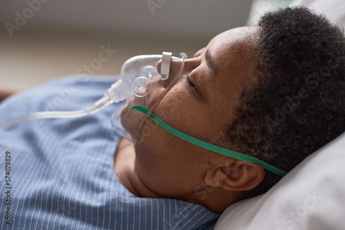 Close up side view of black senior woman with oxygen support mask in hospital room