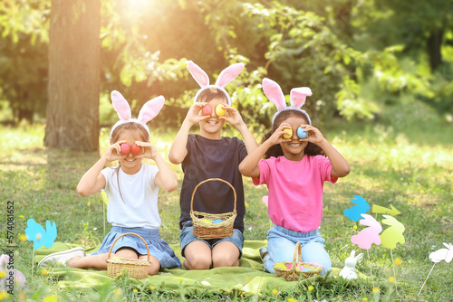 Cuadro en lienzo Little children with painted eggs in park. Easter hunt