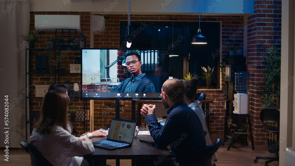 Employees talking with team leader in remote business meeting videocall zoom in, diverse people talking in videoconference at night time. Office workers chatting in teleconference Employees talking with team leader in remote business meeting videocall zoom in, diverse people talking in videoconference at night time. Office workers chatting in teleconference