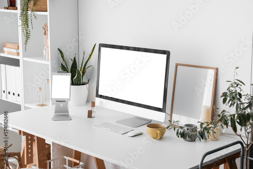 Modern workplace with computer and tablet near light wall © Pixel-Shot