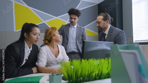 A woman worker in the office at the computer is upset, made a mistake, is almost crying. Colleagues near the woman try to calm her down, give advice.