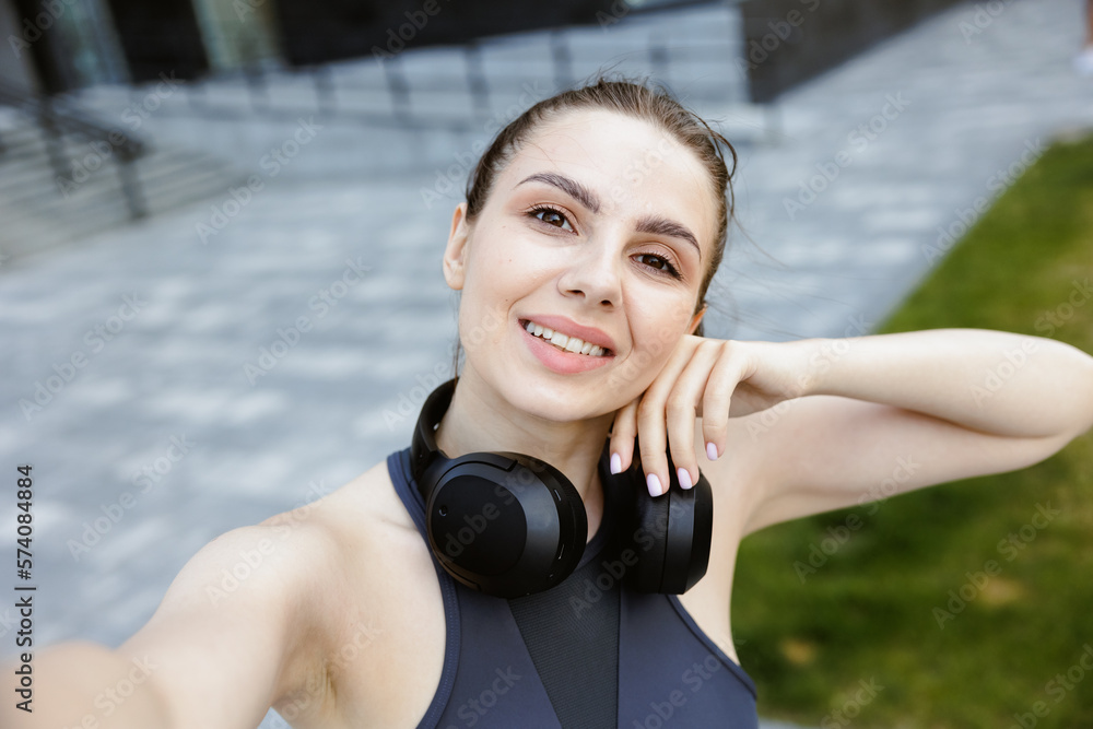 Fototapeta premium Smiling pretty sportswoman taking selfie after workout outdoor.