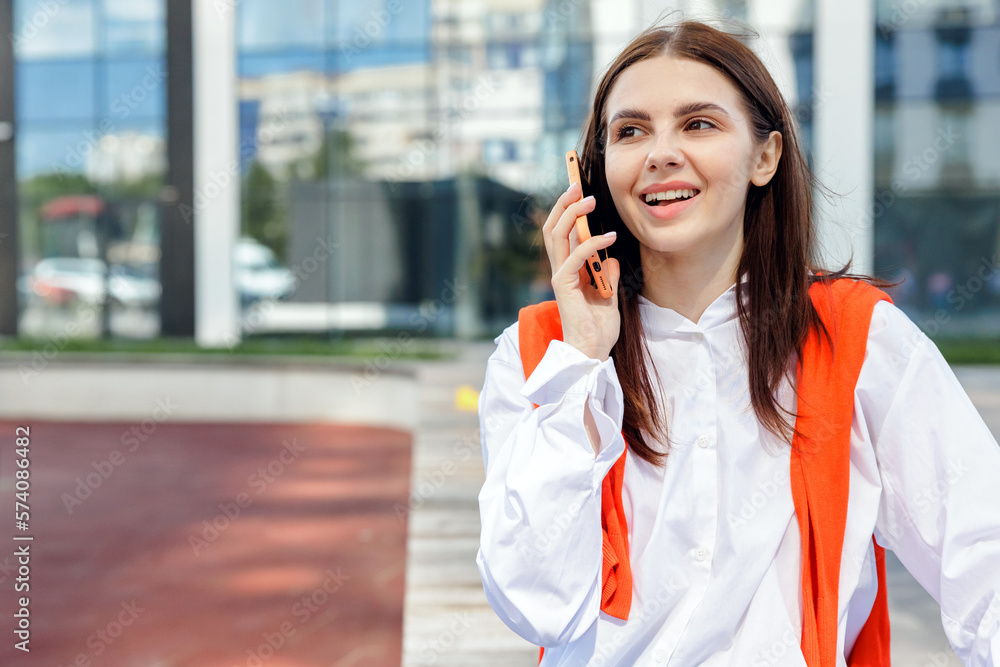 Positive female student speaking on smartphone in downtown. Positive female student speaking on smartphone in downtown.