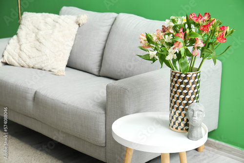 Vase with alstroemeria flowers and decor on table in living room