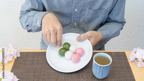 三色団子と桜｜和菓子を食べる男性
