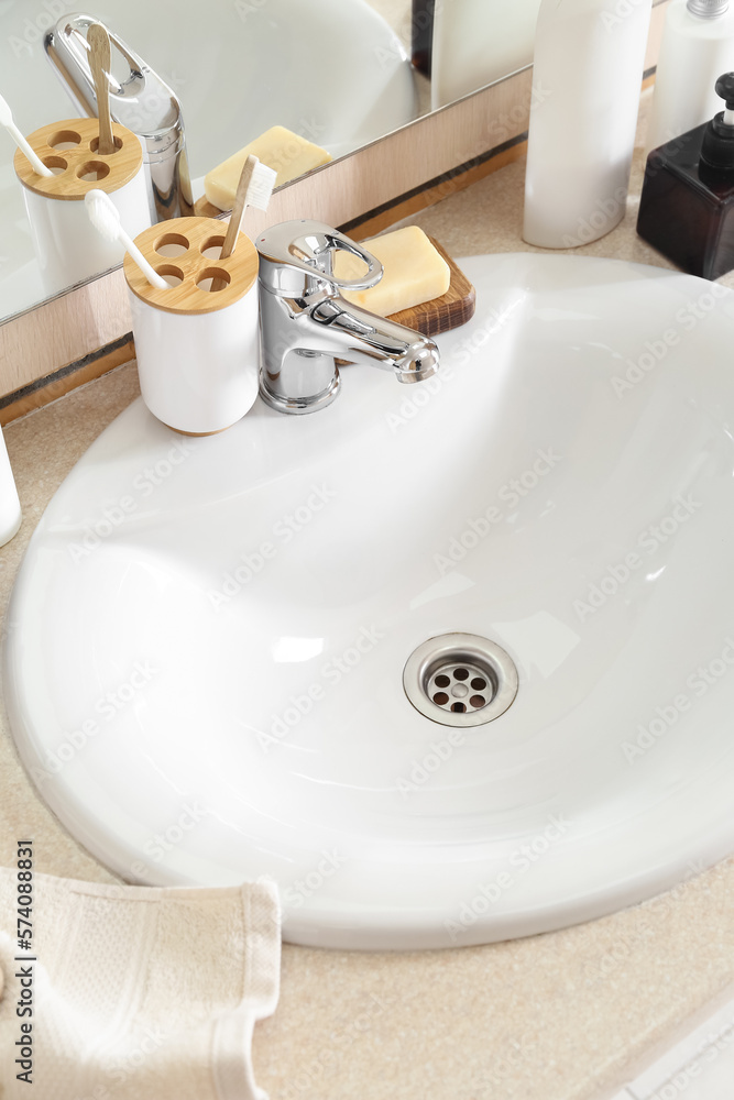 Fototapeta premium Ceramic sink and bath supplies on table, closeup