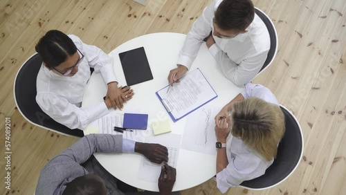 Multi-ethnic group discussing in a meeting while sitting at round table