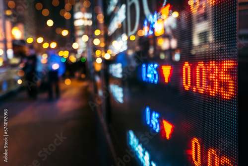 Financial stock exchange market display screen board on the street with and city light reflections, selective focus © Johanna