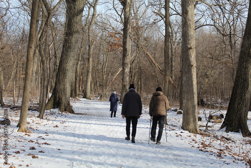 Three people, including two with walking sticks, on the Des Plaines River Trail at Camp Ground Road Woods in Des Plaines, Illinois