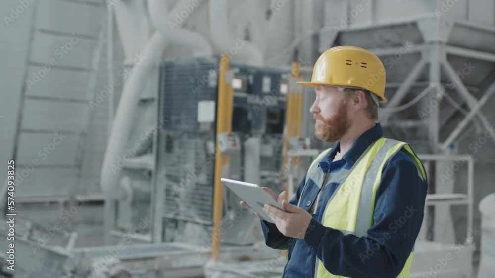 Tracking shot of Caucasian man working in modern marble factory holding digital tablet making rounds to check process Tracking shot of Caucasian man working in modern marble factory holding digital tablet making rounds to check process