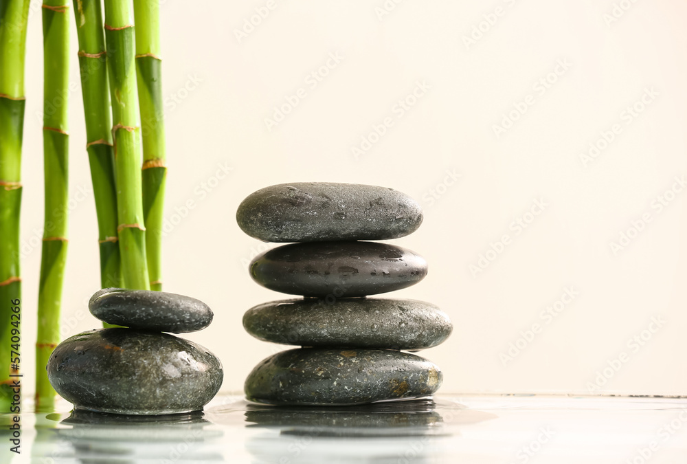 Stack of spa stones and bamboo in water on light background Stack of spa stones and bamboo in water on light background