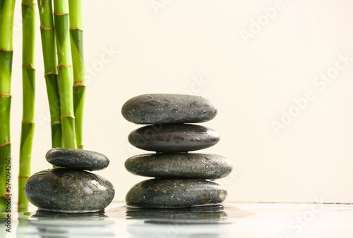 Stack of spa stones and bamboo in water on light background