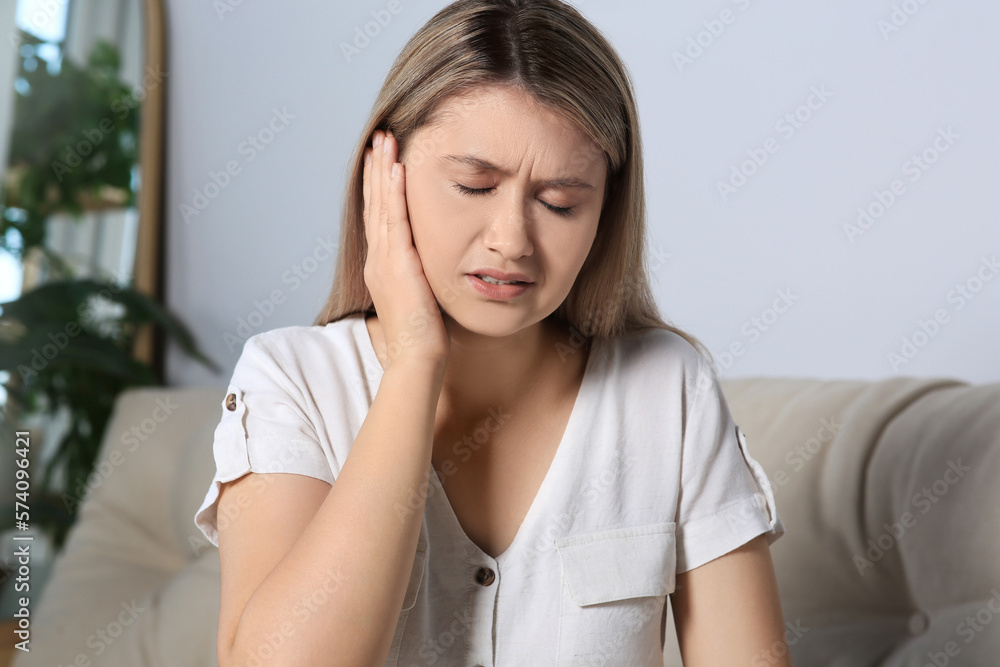 Young woman suffering from ear pain at home Young woman suffering from ear pain at home