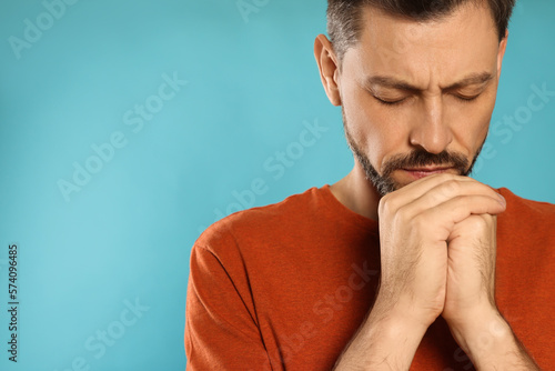 Leinwand Poster Man with clasped hands praying on turquoise background