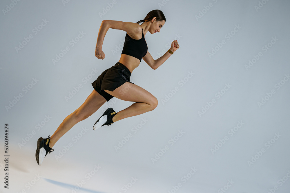 Athletic active woman jumping on studio background. Dynamic movement Athletic active woman jumping on studio background. Dynamic movement