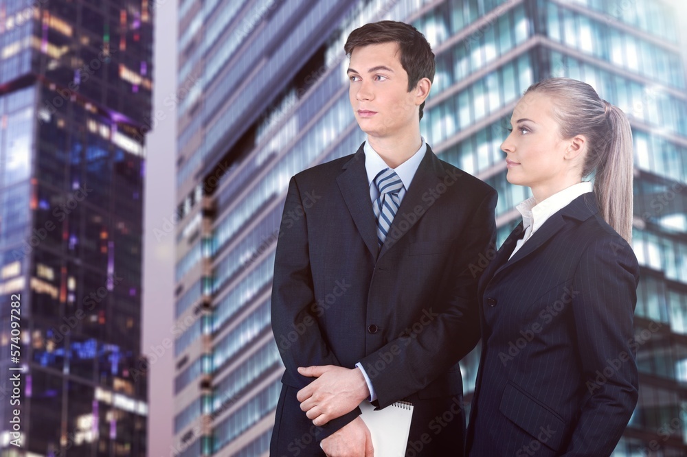Business partners standing and posing with skyscraper background Business partners standing and posing with skyscraper background