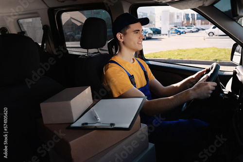 Courier with clipboard and parcels in car. Delivery service