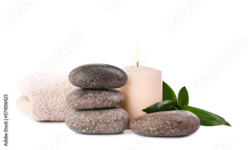 Spa stones, candle, towel and bamboo leaves on white background