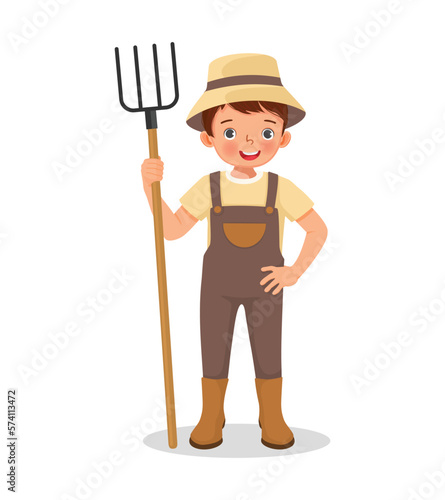 Cute little boy farmer holding a rake working in the farm
