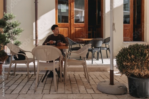 Asian tourist man having a coffee in a cafe in tourist area in Albania.
