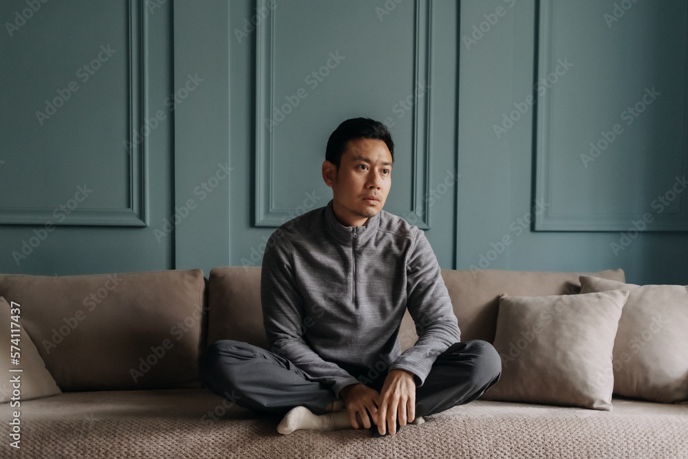 Asian man in fleece sitting in the living room in cold weather. Asian man in fleece sitting in the living room in cold weather.