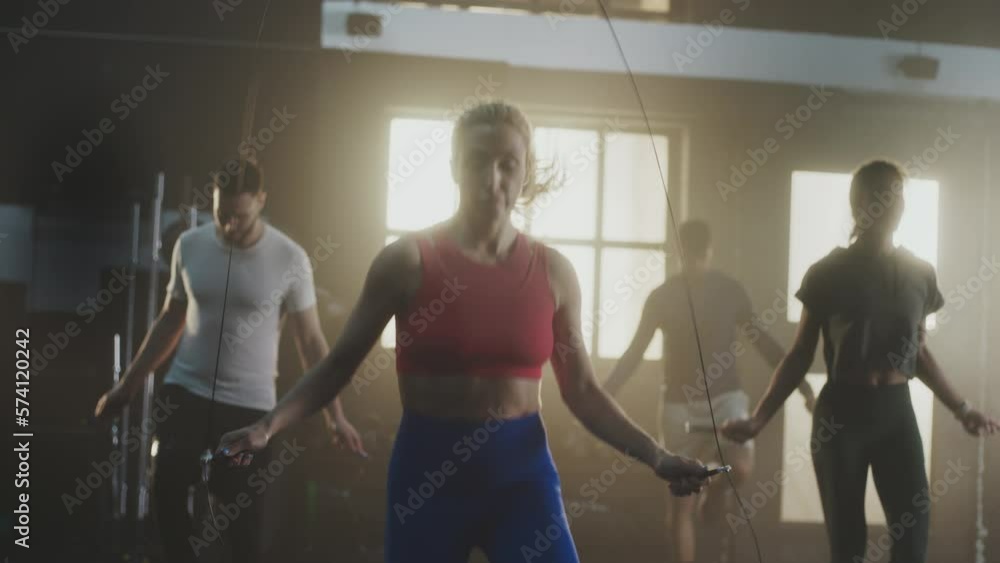 A group of strong athletic men and a women working out with skipping ropes in urban gym. Shot in slow-motion A group of strong athletic men and a women working out with skipping ropes in urban gym. Shot in slow-motion