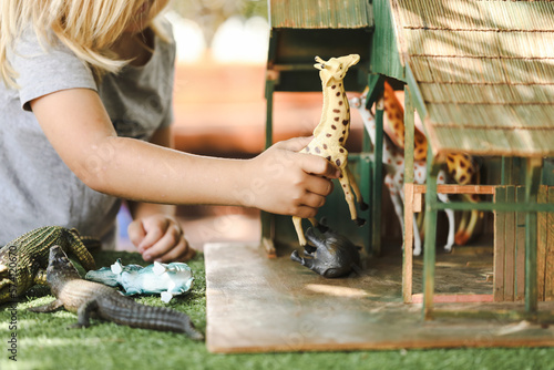 Fototapeta Naklejka Na Ścianę i Meble -  Preschool child playing with jungle animal toy set outdoors at kindergarten