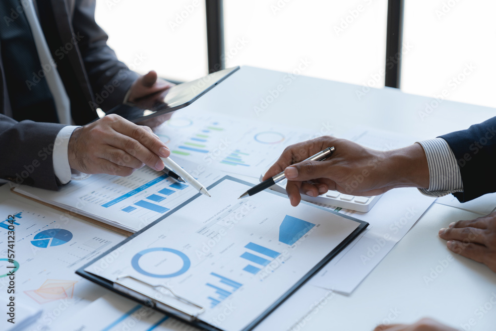 Group of Asian business people meeting new startup project pointing discussion graph and data analysis charts and graphs business finance inside office accounting concept management renew. Group of Asian business people meeting new startup project pointing discussion graph and data analysis charts and graphs business finance inside office accounting concept management renew.